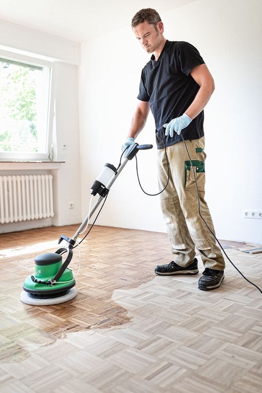 De vakman masseert de Osmo 2K Houtolie in het houtoppervlak met het FloorXcenter.